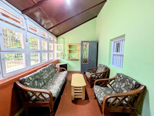 a waiting room with a couch and chairs and a table at Thanmaya Homestay in Chikmagalūr