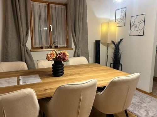 a dining room table with chairs and a vase with flowers at Schönes Wohnen am Wolfgangsee in Sankt Gilgen