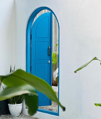 una porta blu in una stanza bianca con una pianta di Liv Inn Iyra - Boutique Stay a Varkala