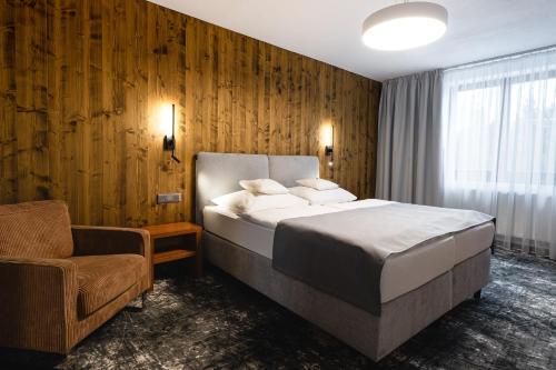 a bedroom with a large bed and a chair at Hotel Horal in Rožnov pod Radhoštěm