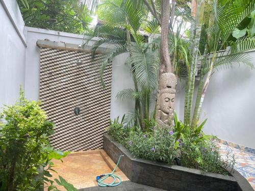 a garden with a statue of a face next to a tree at Bali Santi Bungalows in Candidasa