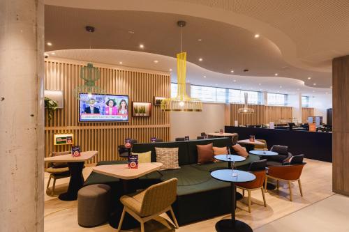 un restaurante con mesas, sillas y TV en Hampton By Hilton Vienna City West, en Viena