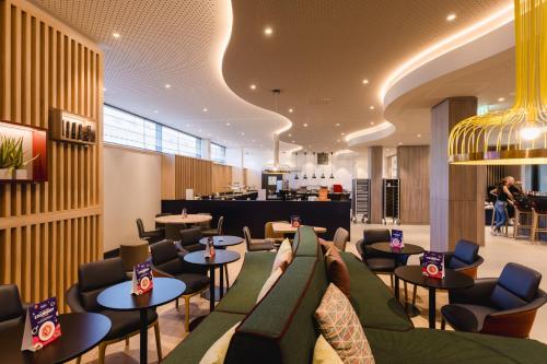 un restaurante con sofás, mesas y sillas en Hampton By Hilton Vienna City West, en Viena