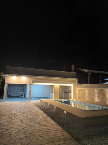 una casa con piscina por la noche en Casa 50m do mar, en Matinhos