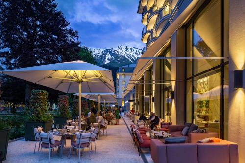 Kempinski Palace Engelberg في إنغيلبرغ: مطعم به طاولات وكراسي ومظلات