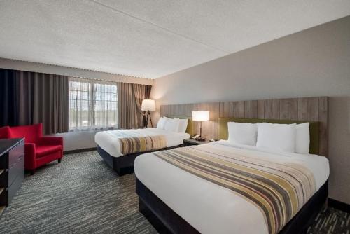 a hotel room with two beds and a red chair at Country Inn & Suites by Radisson, Fredericksburg South I-95 , VA in Fredericksburg