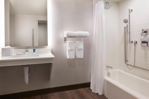 y baño con ducha, lavabo y bañera. en Four Points by Sheraton Windsor Downtown, en Windsor