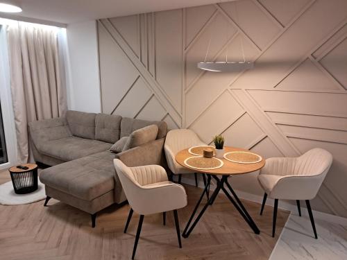 een woonkamer met een bank en een tafel en stoelen bij Apartament KOŚCIUSZKI in Olecko