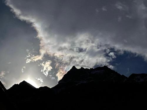 Un ciel nuageux au-dessus des montagnes avec le soleil derrière lui dans l'établissement Montaz Suite and Sauna, à Valtournenche