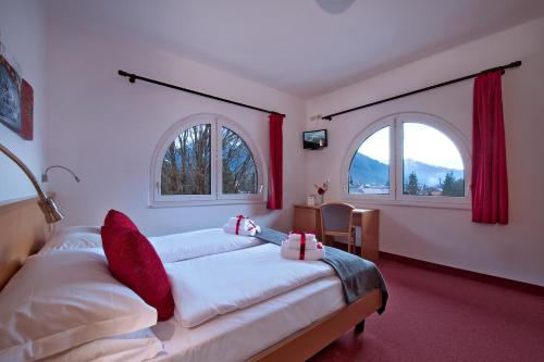 a bedroom with two beds and two windows at GH Hotel Piaz in Pozza di Fassa