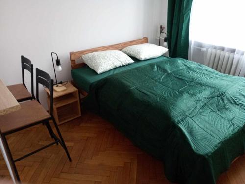 - une chambre avec un lit doté d'une couette verte et d'une chaise dans l'établissement TomTom Hostel, à Cracovie