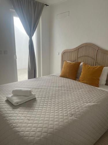 a white bed with two towels on top of it at Galagana Charm House in Golegã