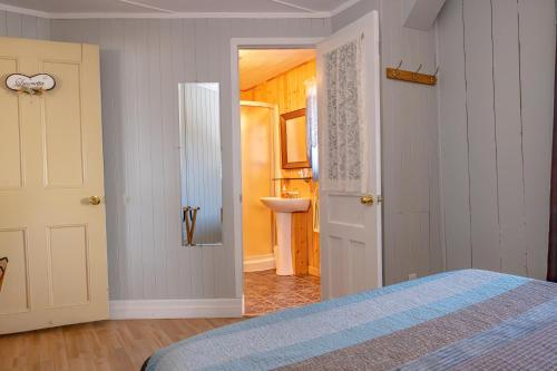 a bedroom with a bed and a bathroom with a sink at Gite la Maison Rochefort in Baie-Sainte-Catherine