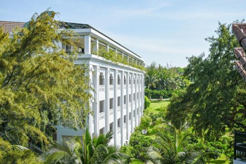 un bâtiment blanc avec des arbres devant lui dans l'établissement Muine Bay Resort, à Mui Ne