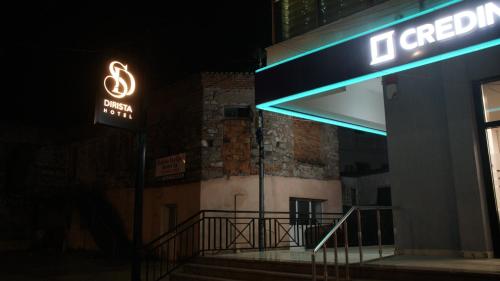 a neon sign in front of a building at night at Hotel Dirista in Shkodër