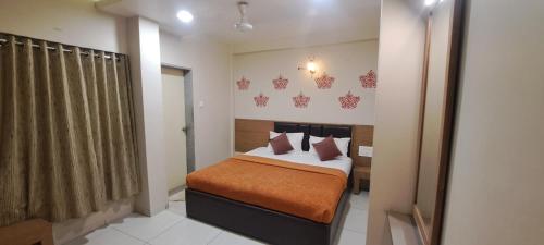 - une chambre avec un lit et une couverture orange dans l'établissement Central Lodge, Kolhapur, à Kolhapur