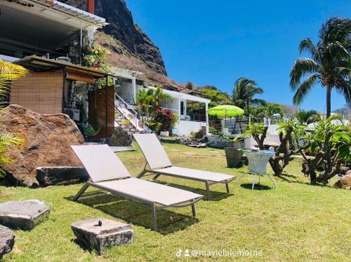 two chairs and an umbrella in front of a house at Residence Ma Vie Là Ltee in Le Morne