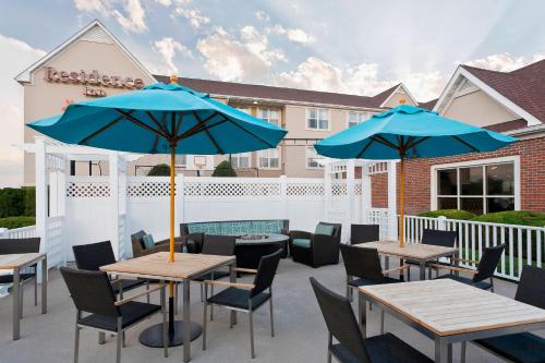 eine Terrasse mit Tischen, Stühlen und blauen Sonnenschirmen in der Unterkunft Residence Inn by Marriott Amarillo in Amarillo