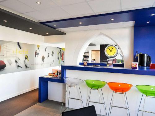 una sala d'attesa con tre sgabelli e un bancone con orologio di ibis Styles Vannes Gare Centre a Vannes