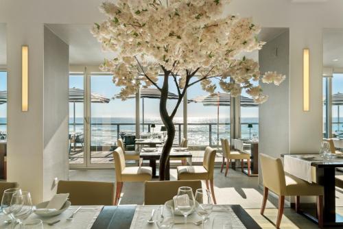 ein Restaurant mit einem Baum, Tischen und Stühlen in der Unterkunft Arribas Sintra Hotel in Sintra