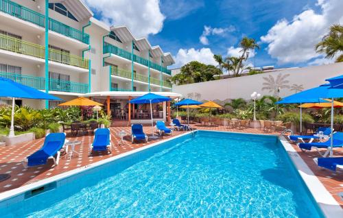 une piscine avec des chaises et des parasols bleus dans un hôtel dans l'établissement Blue Horizon Hotel, à Bridgetown