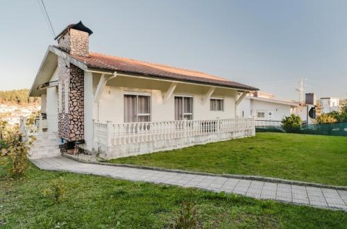 una casa con una recinzione bianca e un cortile di Casa Familiar - Espaçosa, confortável e sossegada a Pevidem