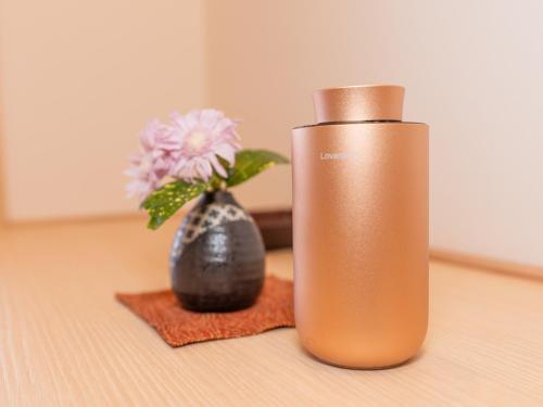 a bronze water bottle next to a vase with a flower at Aburaya Tousen in Yamanouchi