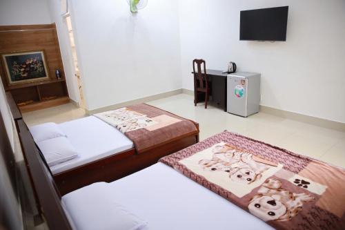 a room with three beds and a television in it at Khách sạn Bảo Lộc Garden in Bao Loc