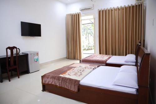 a bedroom with two beds and a television in it at Khách sạn Bảo Lộc Garden in Bao Loc