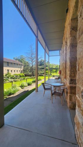 eine Terrasse mit einem Tisch, Stühlen und einer Steinmauer in der Unterkunft St Joseph's Spirituality and Education Centre 