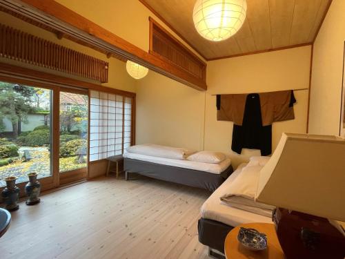 Cette petite chambre comprend 2 lits et une fenêtre. dans l'établissement Den Japanske Have B & B, à Herning