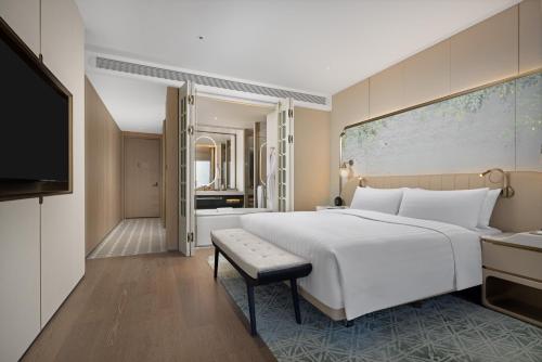 una camera da letto con un grande letto bianco e una televisione di Shangri-La Nanshan, Shenzhen a Shenzhen