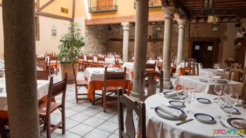 um restaurante com mesas e cadeiras com toalhas de mesa brancas em Hotel Las Cancelas em Ávila