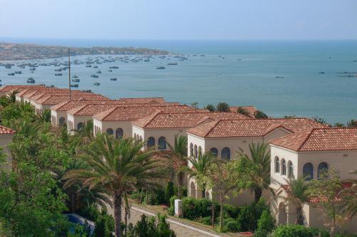 een rij huizen met palmbomen en het water bij Centara Mirage Resort Mui Ne in Mũi Né