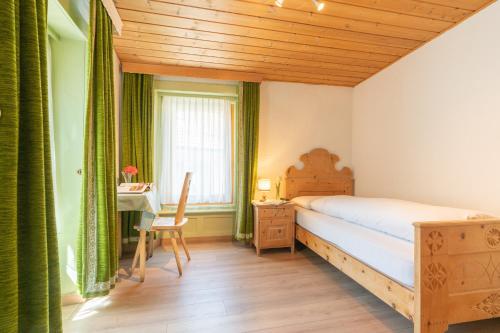 a bedroom with a bed and a desk and a window at Hotel Alpina in Zernez