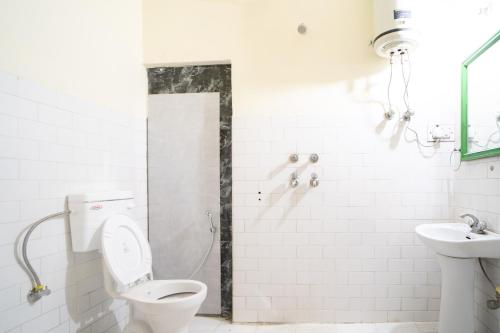 a white bathroom with a toilet and a sink at Timberwolves in Manāli