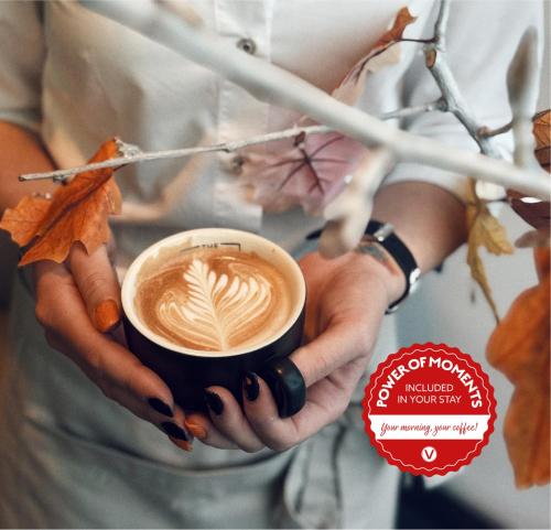 una mujer sosteniendo una taza de café en sus manos en Vienna House Easy by Wyndham Pilsen, en Plzeň