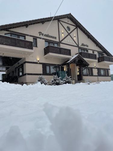 een groot gebouw met sneeuw ervoor bij Pensiunea Maria in Colibiţa