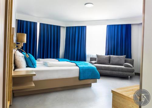 Schlafzimmer mit blauen Vorhängen, einem Bett und einem Sofa in der Unterkunft Hotel Atlas Halle in Halle an der Saale