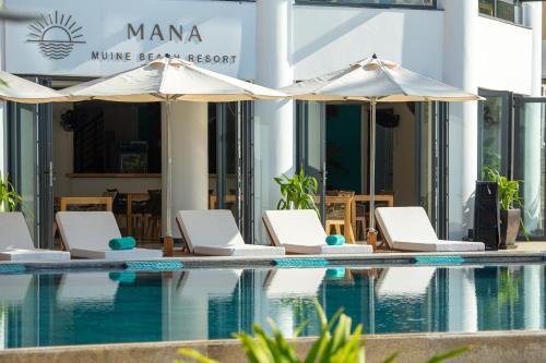 una piscina con sedie e ombrelloni accanto a un edificio di Mana Mui Ne Beach Resort & Spa a Mui Ne