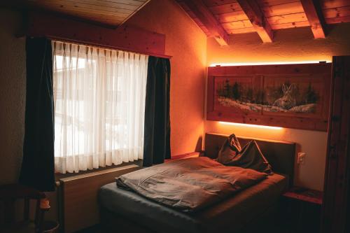 a small bed in a room with a window at Pension Sonne in Adelboden