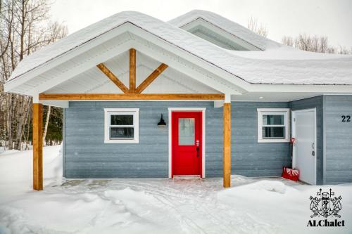 una casa blu con una porta rossa nella neve di Le Loonix- Chalet familiale avec Spa a Petite-Rivière-Saint-François