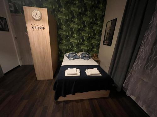 Cette petite chambre comprend un lit avec des serviettes et un réveil. dans l'établissement Apartamenty Stary Rynek 18, à Łomża