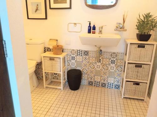 a bathroom with a toilet and a sink at Beach House Babylon guest house with kitchenette and garden in Torreira