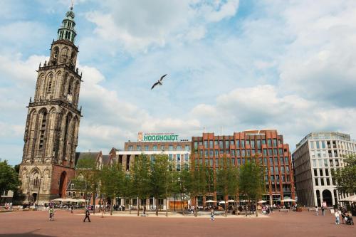 un pájaro sobrevolando una ciudad con una torre de reloj en The Market Hotel, en Groninga