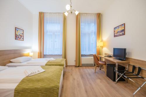 Baross City Hotel - Budapest في بودابست: غرفة فندقية بسريرين ومكتب