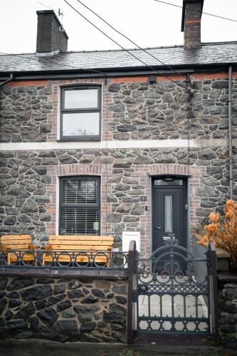 een stenen huis met een bankje ervoor bij Snowdonia Quarryman cottage in Llanberis