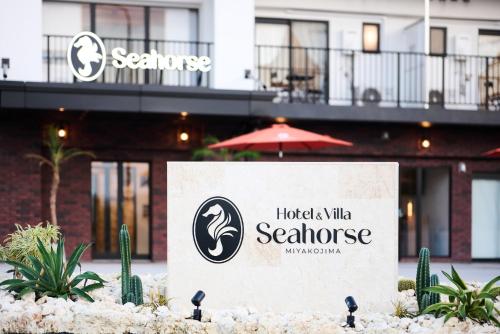 ein Schild vor einem Hotel mit einem Gebäude in der Unterkunft Hotel & Villa Seahorse MIYAKOJIMA in Miyako-jima