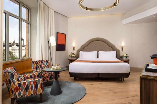 ein Hotelzimmer mit einem Bett und einem Stuhl in der Unterkunft NH Collection Madrid Paseo del Prado in Madrid