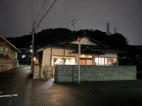 ein kleines Gebäude mit einem Schild davor in der Unterkunft Wholeearth Ryokan Hiroshima in Hiroshima